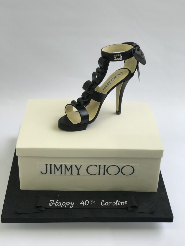 novelty cake shaped like a black strappy high heel Jimmy Choos on a white designer shoe box